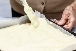 Close up of sponge cake dough being poured into a baking tin photo