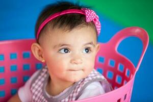 hermosa diez meses bebé niña jugando en un rosado cesta. temprano estímulo para niños pequeños concepto. foto