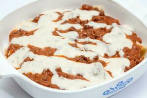 Parmesan Lasagne Preparation. Adding white sauce to the lasagna photo