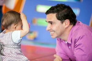 hermosa diez meses bebé niña jugando con su papá. temprano estímulo para niños pequeños concepto. foto