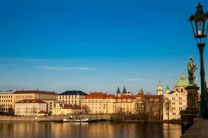 Boat on Vlava river at sunset in Prague seen from the iconic Charles Bridge photo