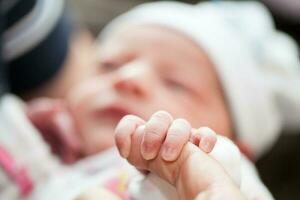 Closeup of a newborn hand and her father finger at hospital on the day of her birth. Fatherhood concept photo