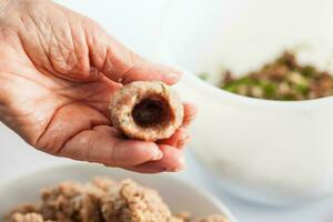 Step by step Levantine cuisine kibbeh preparation. Close up of a senior woman hands shaping a kibbeh photo