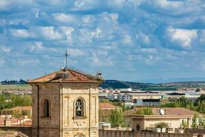 cigüeñas anidamiento en parte superior de el campana torre de Iglesia de carmen Delaware abajo construido en el 15 siglo en el ciudad de salamanca en España foto