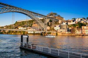 Modern boat and the Dom Luis I Bridge a metal arch bridge over the Douro River between the cities of Porto and Vila Nova de Gaia in Portugal inaugurated in 1886 photo