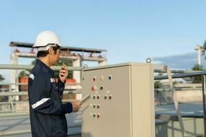 Mechanic or maintenance or electrical engineer checking main electrical control systems industrial plant. Utility fore man daily check power systems in process. Main Distribution Board, Switchboards photo