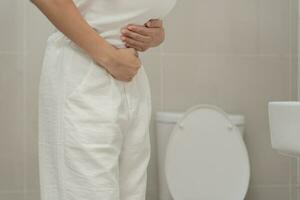 Constipation and diarrhea in bathroom. Hurt woman touch belly  stomach ache painful. colon inflammation problem, toxic food, abdominal pain, abdomen, constipated in toilet, stomachache, Hygiene photo