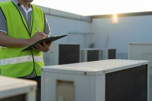 Asian maintenance engineer works on the roof of factory. contractor inspect compressor system and plans installation of air condition systems in construction. Checklist, inspector, control photo