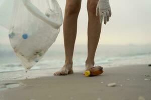 ahorrar agua. los voluntarios recogen basura en la playa y las botellas de plástico son difíciles de descomponer para evitar dañar la vida acuática. tierra, ambiente, planeta verde, reducir el calentamiento global, salvar el mundo foto