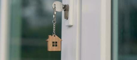 Landlord key for unlocking house is plugged into the door. Second hand house for rent and sale. keychain is blowing in the wind. mortgage for new home, buy, sell, renovate, investment, owner, estate photo