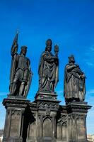 Antique statue of Saints Norbert of Xanten, Wenceslas and Sigismund on the medieval gothic Charles Bridge in Prague built on the 15th century photo