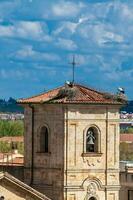 cigüeñas anidamiento en parte superior de el campana torre de Iglesia de carmen Delaware abajo construido en el 15 siglo en el ciudad de salamanca en España foto
