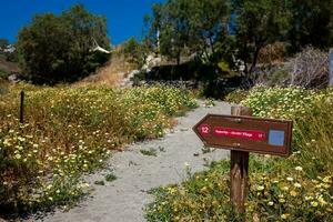 Arrow sign of the walking path number 12 to Akrotiri village in Santorini Island in a beautiful early spring day photo