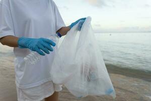 salvar océano. voluntario recoger arriba basura basura a el playa y el plastico botellas son difícil descomponer evitar daño acuático vida. tierra, ambiente, verdeado planeta, reducir global calentamiento, salvar mundo foto