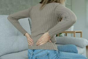 woman holding her lower back while and suffer from unbearable pain health and problems, chronic back pain, backache in office syndrome, scoliosis, herniated disc, muscle inflammation photo