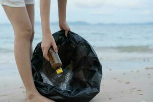 salvar océano. voluntario recoger arriba basura basura a el playa y el plastico botellas son difícil descomponer evitar daño acuático vida. tierra, ambiente, verdeado planeta, reducir global calentamiento, salvar mundo foto