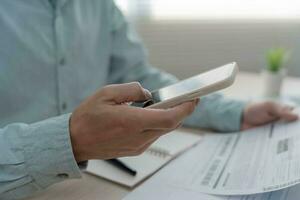 business man use phone to scan barcode or QR codes to pay credit card bill after receiving document invoice online. payment, receive, paying electricity, digital payments without money, technology photo