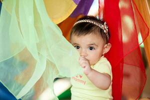 Beautiful ten months baby girl playing with colorful fabrics. Early stimulation for toddlers concept. photo