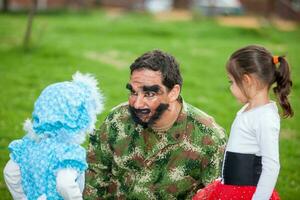 Young father wearing a woodcutter costume playing with his daughters. Real family having fun while using costumes of the Little red riding hood tale in Halloween. photo