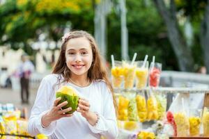 Beautiful young girl at Paseo Bolivar Square in the city of Cali eating tropical fruits in Colombia photo