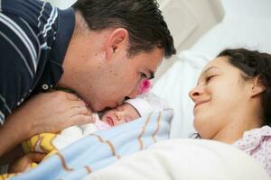 joven madre y padre con su recién nacido bebé niña a el hospital en el día de su nacimiento. familia concepto. paternidad concepto foto