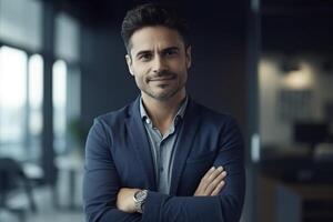 Portrait of handsome businessman with crossed arms smiling at camera in office photo