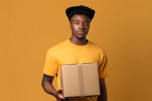 Smiling African American delivery man holding cardboard box isolated on yellow background photo