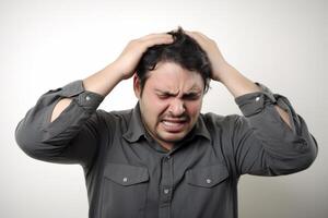 Frustrated young man with a headache isolated on a white background photo