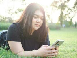 Portrait young woman asian chubby cute beautiful one person wear black shirt look hand holding using smart phone in garden park outdoor evening sunlight fresh smiling cheerful happy relax summer day photo