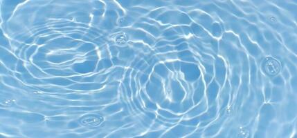 Blue water with ripples on the surface. Defocus blurred transparent blue colored clear calm water surface texture with splashes and bubbles. Water waves with shining pattern texture background. photo