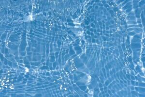 Blue water with ripples on the surface. Defocus blurred transparent blue colored clear calm water surface texture with splashes and bubbles. Water waves with shining pattern texture background. photo