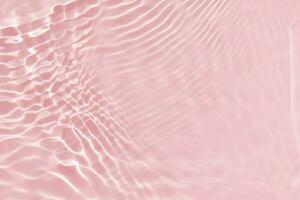 Pink water with ripples on the surface. Defocus blurred transparent white colored clear calm water surface texture with splashes and bubbles. Water waves with shining pattern texture background. photo