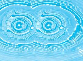 Blue water with ripples on the surface. Defocus blurred transparent blue colored clear calm water surface texture with splashes and bubbles. Water waves with shining pattern texture background. photo