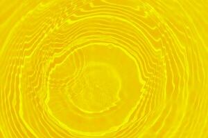Yellow water with ripples on the surface. Defocus blurred transparent gold colored clear calm water surface texture with splashes and bubbles. Water waves with shining pattern texture background. photo