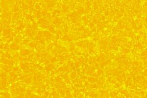 Yellow water with ripples on the surface. Defocus blurred transparent gold colored clear calm water surface texture with splashes and bubbles. Water waves with shining pattern texture background. photo