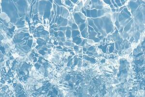 Blue water with ripples on the surface. Defocus blurred transparent blue colored clear calm water surface texture with splashes and bubbles. Water waves with shining pattern texture background. photo