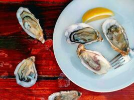 fresh shelled oysters With a slice of lentils and a fork in a plate, on a wooden table, there's a clam on the table. photo