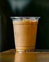 Milk tea, iced tea, Thai iced tea, iced tea in plastic glass on table. Dark background. photo