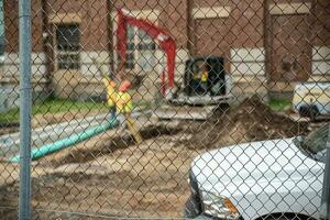 Construction site behind the fence Workers are working, loaders, sand piles and pipes. photo