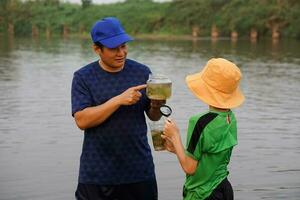 Asian man teacher is teaching his student outdoor, study ecology subject, explore water from nature source. Concept,Education. Learning by doing. Life experience photo