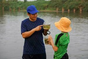 asiático hombre profesor es enseñando su estudiante exterior, estudiar ecología sujeto, explorar agua desde naturaleza fuente. concepto, educación. aprendizaje por haciendo. vida experiencia foto