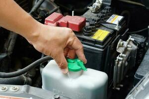 Closeup hand hold bottle tank of car engine coolant. Concept, automobile maintenance. Check and repair before driving for safety. Basic diagnose vehicle problems. photo