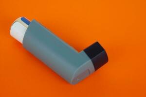 Asthma inhalers on orange background. Concept, Pharmaceutical products for treatment symptoms of asthma or COPD. Use under prescription. Health care device at home. photo