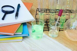 Science equipment, pile of books placed besides transparent beaker, test tubes, dropper and chemical liquid. Concept, Science lesson, experiment equipment and tools. photo