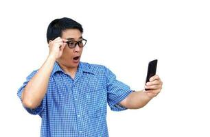 Asian man wears eyeglasses, holds and looks at smartphone, feels excited, isolated on white background. Concept, wow , surprised expression feeling to know good news. photo