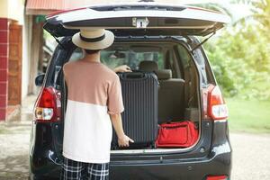 espalda ver de hombre es que lleva maletas, equipaje dentro coche maletero para un viaje. concepto, de viaje, yendo por coche. vacaciones, fiesta o fin de semana viaje. preparar y Listo ir. foto