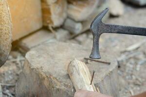 Closeup carpenter use old hammer to hit metal nail on wood.  Concept, carpentry and construction tools. Repair or fixing, DIY woodwork.  Local lifestyle. photo