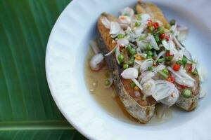 Deep fried sliced King mackerel salad on white plates . Concept ,Cooking. Seafood. Delicious menu that Thai people eat with rice and variety menu with salty fish. Thai cuisine. Banana leaf background photo
