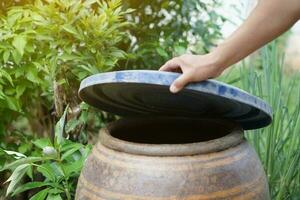 Closeup hand hold lid to cover water bucket to protect from mosquito to breed inside or other  insects or dust go into water. Concept, campaign to stop mosquitoes cycle to lay eggs in water container photo