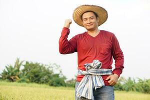 Happy  handsome Asian man farmer , stands at paddy field. Feel happy, confident and proud in crops. Concept , Agricultural occupation. Thai farmer. photo